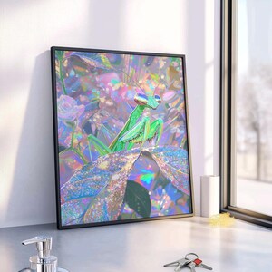 May include: A framed wall art print featuring a vibrant, iridescent green praying mantis perched on a large leaf. The artwork displays a colorful, holographic-style background with shimmering pink, blue, and purple light effects and floral shapes.