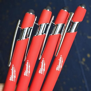 May include: Four red stylus pens with silver accents and the "Milwaukee" logo. Each pen has a black tip and a silver clip. The pens are designed for use with touch screen devices.
