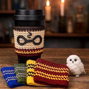 May include: A black travel mug with a crocheted sleeve featuring a black and tan design with a black glasses and lightning bolt symbol. Additional crocheted cozies in blue, green, yellow, and burgundy with striped patterns are displayed.