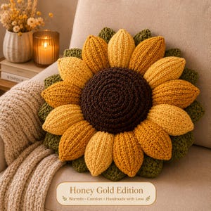 May include: A round, crocheted sunflower pillow featuring a dark brown center surrounded by layered yellow and orange petals, with dark green leaves at the base. A rectangular label at the bottom displays the text Honey Gold Edition.