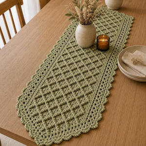 Peut inclure: Un chemin de table rectangulaire en crochet vert sauge présentant un motif en losanges et une bordure festonnée. Le chemin de table est réalisé avec un fil texturé et affiche un design ajouré cohérent sur toute sa longueur et sa largeur.