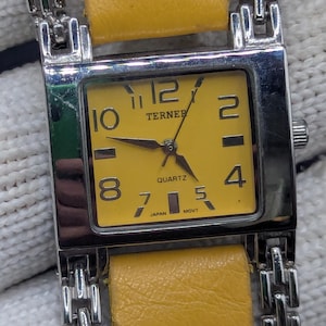 Reloj de cuarzo vintage Bijoux Terner con esfera amarilla, modelo K-1085S, con correa de acero inoxidable y detalles de cuero.