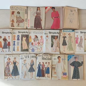 May include: A collection of seventeen vintage sewing patterns from brands including McCall's, Simplicity, New Look, and Style. Each paper envelope features illustrations of various garment designs, including dresses, skirts, and blouses, with printed brand names.