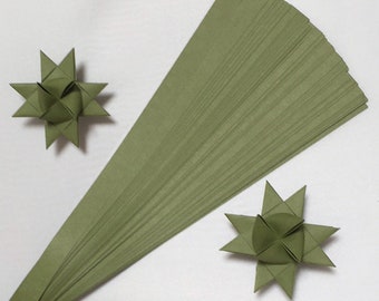 May include: A bundle of 50 green paper strips for making origami stars. The strips are about 1/2 inch wide and 12 inches long. Two finished origami stars are shown in the image.