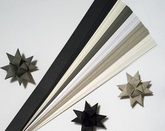 May include: A collection of 18 paper strips in various shades of gray, white, and black. The strips are arranged in a fan shape, with the darkest shades at the bottom and the lightest shades at the top. Three origami stars are also visible in the image, two in gray and one in black.