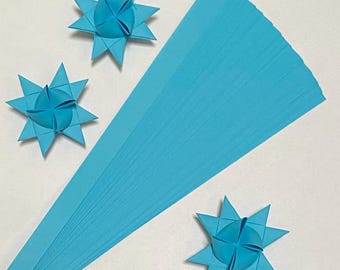 May include: A stack of 50 light blue origami paper strips. The paper is 5/16 inch wide and 11 inches long. Three origami stars are folded from the paper.