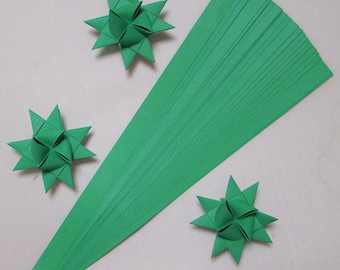 May include: A stack of green paper strips for origami, with three finished green origami stars.