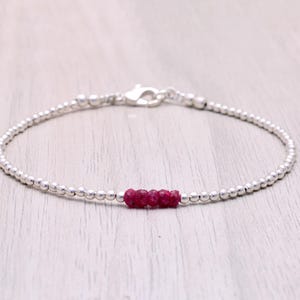 Puede incluir: Una delicada pulsera de plata con pequeñas cuentas redondas y un grupo de vibrantes piedras de rubí rojo. La pulsera se asegura con un cierre de plata y está diseñada para una estética minimalista. La pulsera mide aproximadamente 17,8 cm de largo.