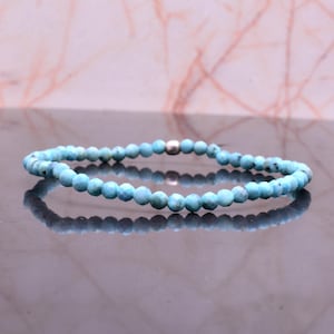 Può includere: Un braccialetto di perline turchesi con chiusura argentata. Il braccialetto è composto da piccole perline sfaccettate in varie tonalità di blu-verde. Le perline sono infilate per formare una fascia flessibile.