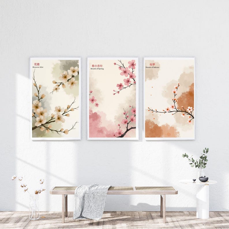 K&ouml;nnte beinhalten: Drei gerahmte Kunstdrucke mit Aquarellillustrationen von Kirschbl&uuml;tenzweigen. Die Drucke haben einen wei&szlig;en Rand und sind vor einem neutralen Hintergrund mit sanften Farbt&ouml;nen in Rosa, Beige und Braun platziert. Japanischer Text ist sichtbar.