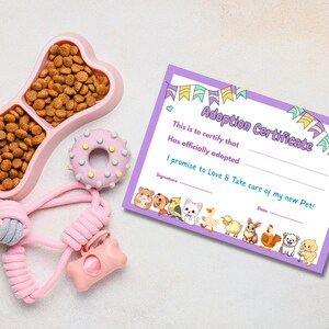 May include: A pink dog bone-shaped food bowl filled with brown kibble, a pink donut-shaped toy, a pink rope toy, and a pink bone-shaped bag dispenser. A purple adoption certificate with the text "Adoption Certificate" and cute animal illustrations.