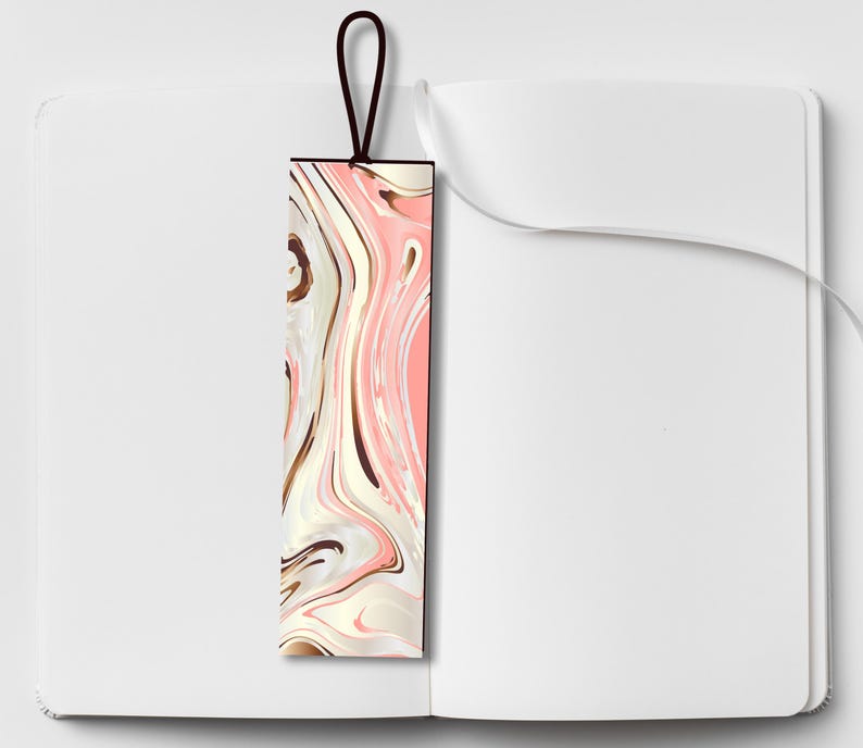 Pu&ograve; includere: Un segnalibro rettangolare con un design marmorizzato rosa, bianco e marrone. Il segnalibro ha un bordo nero e un anello marrone scuro nella parte superiore. Il segnalibro &egrave; posto all'interno di un quaderno bianco aperto.