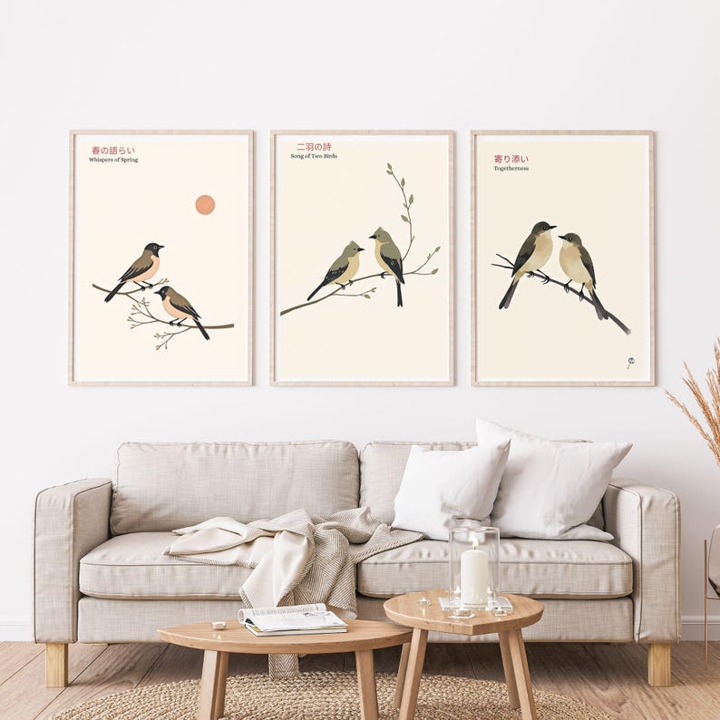 K&ouml;nnte beinhalten: Set aus drei gerahmten Kunstdrucken mit Illustrationen von V&ouml;geln auf &Auml;sten. Jeder Druck hat einen cremefarbenen Hintergrund mit japanischem Text und englischen &Uuml;bersetzungen. Die Drucke werden &uuml;ber einem beigen Sofa mit h&ouml;lzernen Beistelltischen ausgestellt.