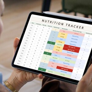 May include: A person holds a black tablet displaying a "NUTRITION TRACKER" spreadsheet. The tracker shows columns for date, protein, fiber, water, veg servings, meal quality, nutrition day type, and nutrition score. A white stylus rests on the tablet.