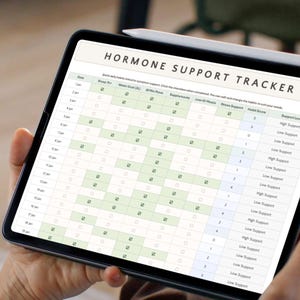 May include: A tablet displaying a "HORMONE SUPPORT TRACKER" with a white stylus attached. The tracker features a grid with checkboxes and text, including "Stress Support" and "Support Level". The screen shows a calendar-like layout.