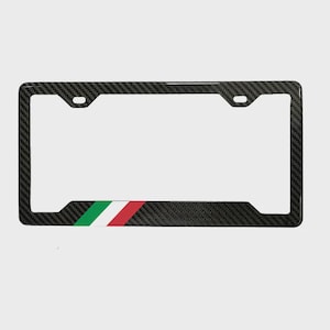 May include: A carbon fiber license plate frame with a green, white, and red stripe design at the bottom. The frame has a textured appearance and is designed to fit a standard U.S. license plate.