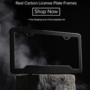 May include: A real carbon fiber license plate frame with a textured weave pattern. The frame is black and rectangular, with rounded corners and mounting holes. The image includes the text "Real Carbon License Plate Frames" and "Shop Now".