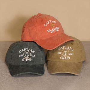 May include: Three baseball caps in shades of orange, green, and tan. Each cap features the word "CAPTAIN" above an anchor design, the text "EST. 2025", and a name. The orange cap also has the text "MR. RAMIREZ".