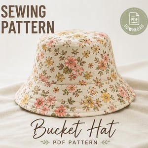Puede incluir: Un sombrero de pescador floral con un fondo crema y flores rosas, amarillas y verdes. Las palabras "SEWING PATTERN" y "Bucket Hat PDF PATTERN" se muestran en escritura marrón. Un icono de descarga PDF está en la esquina superior derecha.