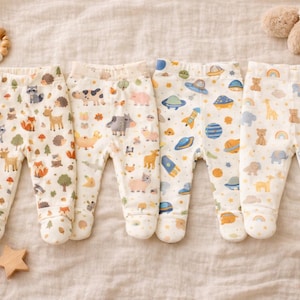 Pode incluir: Quatro pares de pijamas de bebé com pés com diferentes padrões. Um par tem animais da floresta, outro animais da quinta, um terceiro desenhos espaciais e o último arco-íris e ursos. Uma estrela de madeira e um anel de dentição de madeira também são visíveis.