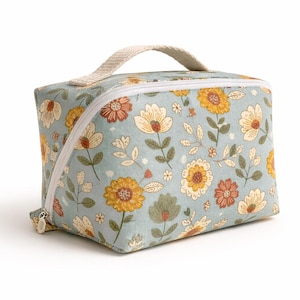 May include: A floral-patterned cosmetic bag with a light blue background. The bag features a repeating pattern of yellow, orange, and white flowers with green leaves. It has a white zipper and a beige handle.