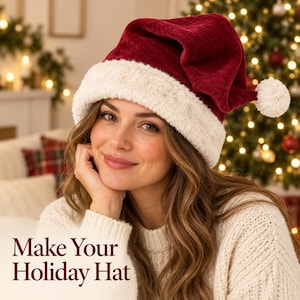 Op de afbeelding: Een dieprode fluwelen kerstmuts met een dikke, crèmekleurige rand van imitatiebont en een bijpassende pompon aan de punt. De tekst "Make Your Holiday Hat" staat in donkerrode letters in de linkerbenedenhoek van de afbeelding.