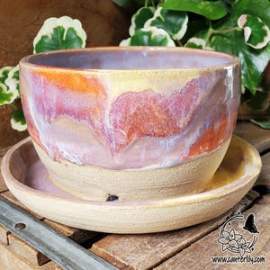 May include: A white ceramic mug with a black handle and the text "But First, Coffee" in a black, handwritten-style font. The mug is on a white surface.