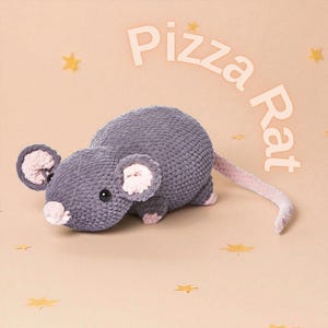 Puede incluir: Un peluche de rata gris con detalles rosas en las orejas, la nariz y la cola. El peluche tiene ojos negros de botón y está tejido a ganchillo. Las palabras "Pizza Rat" están escritas encima de la rata en una fuente lúdica. El fondo es de color beige claro con estrellas.