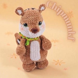 Puede incluir: Un juguete de peluche artesanal de ardilla listada marrón y blanco con una bufanda verde. La ardilla listada tiene una barriga blanca, mejillas rosadas y ojos verdes. La palabra "Chipmunk" está escrita en una fuente curva en la esquina superior derecha.