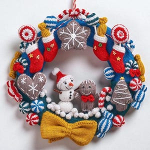 May include: A handmade Christmas wreath with a blue base, adorned with knitted ornaments. Features include red stockings, gingerbread figures, a snowman, and candy. A yellow bow is at the bottom. The wreath is decorated with red and white striped ribbon.