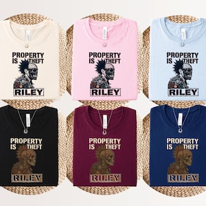 May include: Six t-shirts in cream, pink, light blue, black, maroon, and navy blue. Each shirt features a graphic of a skull with a mohawk and the text "PROPERTY IS THEFT" above the name "RILEY" in a rectangular box on the front of the garment.