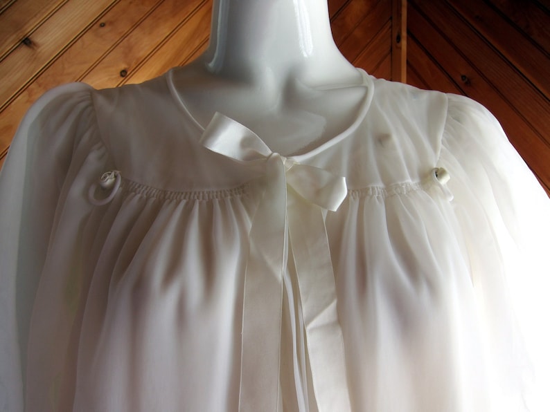 May include: A white sheer robe with a satin ribbon tie and two small buttons on the shoulders.