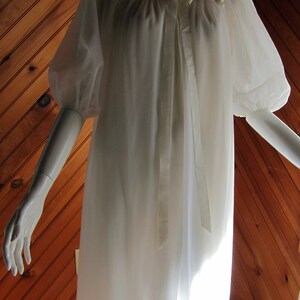 May include: White sheer nightgown with a satin ribbon tie at the neckline and puffed sleeves.