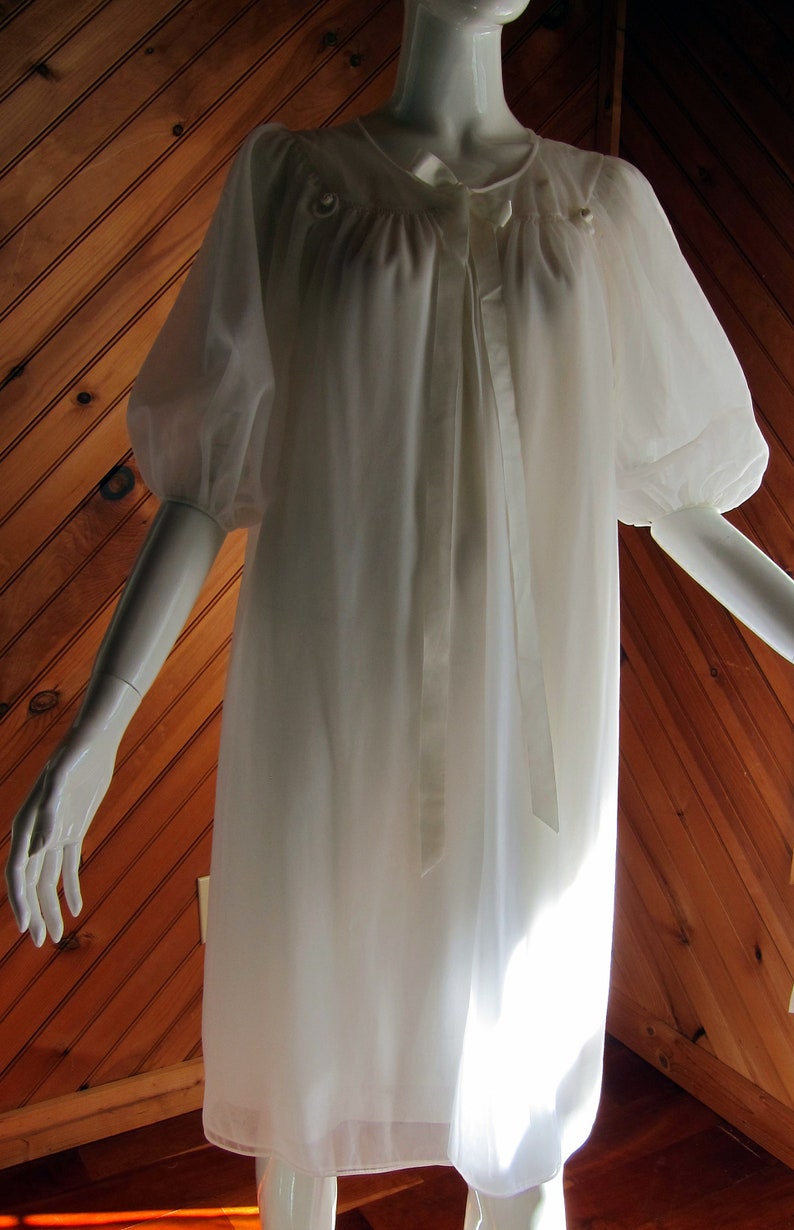 May include: White sheer nightgown with a satin ribbon tie at the neckline and puffed sleeves.