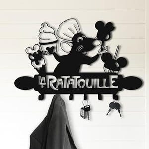 May include: Black metal wall-mounted key holder featuring a silhouette of a chef rat holding desserts, with the text "La Ratatouille". Includes hooks for keys and a hanging jacket. A decorative and functional item.