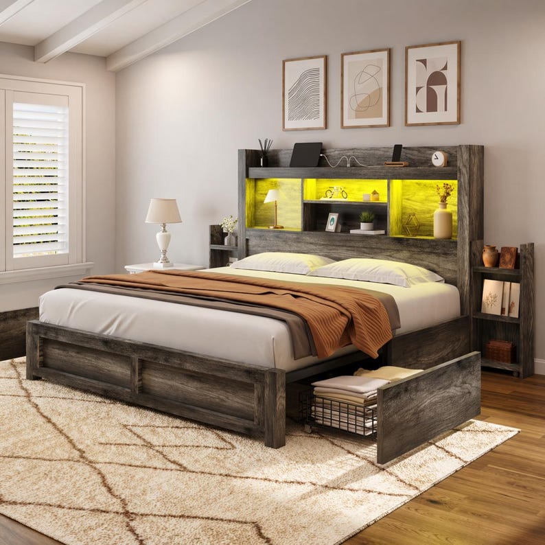 May include: A gray wooden bed frame with a built-in headboard featuring shelves and a yellow-lit display area. The bed has a white comforter, an orange blanket, and a drawer. A beige rug is in the foreground.