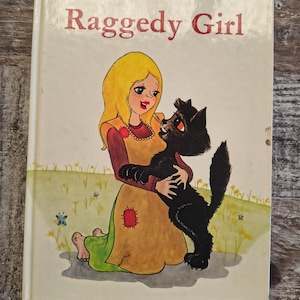 May include: A vintage children's book titled "The Little Raggedy Girl." The cover features an illustration of a girl with blonde hair holding a black cat. The girl wears a yellow dress with a red patch and a green skirt.