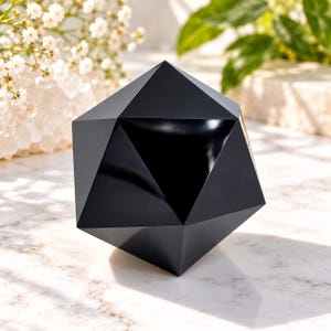 Könnte beinhalten: Eine massive schwarze geometrische Skulptur in Form eines facettenreichen Ikosaeders mit glatten, matten Oberflächen und scharfen, definierten Kanten. Das Objekt zeigt eine komplexe Anordnung dreieckiger Flächen, die eine symmetrische Form bilden.