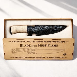 May include: A black obsidian blade with a wrapped handle, presented in a wooden box. The box features the text "BLADE OF THE FIRST FLAME" and "A LEGENDARY OBSISIAN RELIC INSPIRED BY ANCIENT DRAGON MYTHS".