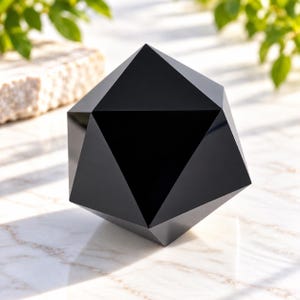 May include: A solid black icosahedron sculpture with a smooth, reflective surface. The geometric object features twenty triangular faces meeting at sharp vertices, creating a symmetrical polyhedral shape with a deep, opaque, and dark finish.