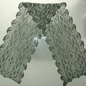 May include: A green knitted scarf with a lacy pattern. The scarf is folded in half and laid flat on a white surface.