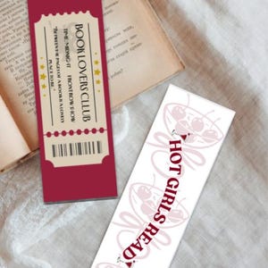 Puede incluir: Dos marcadores de libros sobre un libro. Uno es burdeos con el texto "BOOK LOVERS CLUB" y un diseño de boleto. El otro es blanco con cerezas rosas y el texto "HOT GIRLS READ".