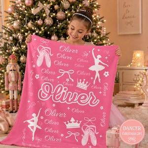 May include: A bright pink fleece blanket featuring a repeating white pattern of ballet slippers, crowns, bows, and silhouettes of a ballerina. The name Oliver is printed in various fonts throughout the design, including a large central script.