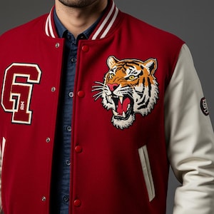 May include: A red varsity jacket with white sleeves and a striped collar. The jacket features a large embroidered tiger head patch and a letter "G" patch. The jacket has red buttons and a white pocket trim.