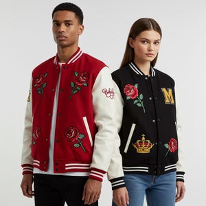 May include: Two varsity jackets, one red and one black, are displayed. The red jacket has white sleeves and rose embroidery. The black jacket has white sleeves, rose and crown embroidery, and a gold "M" patch. Both have striped cuffs and hems.