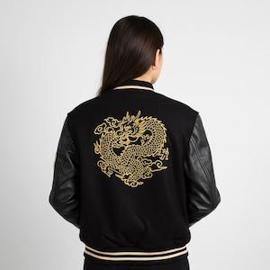 May include: Black varsity jacket with a gold dragon design on the back. The jacket has black leather sleeves, a ribbed collar, and a striped hem. The dragon is intricately detailed.