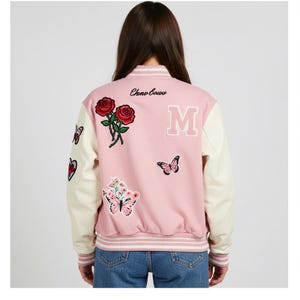 May include: Pink and cream varsity jacket with embroidered roses, butterflies, and a large letter "M". The jacket features the text "Chino Bows" on the back and has cream-colored sleeves and a striped hem.