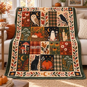 May include: A rectangular throw blanket featuring a patchwork design with autumn-themed illustrations including an owl, a black cat, pumpkins, a ghost, mushrooms, and the name CHARLOTTE. The border displays leaves and berries.