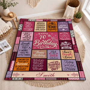 May include: A rectangular throw blanket featuring a patchwork design with various inspirational quotes and birthday messages in shades of pink, purple, and orange. The center text reads Happy 70th Birthday To You, with the name Smith at the bottom.