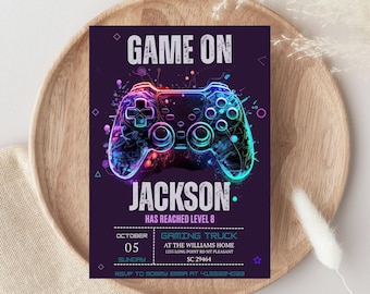以下が含まれることがあります： ネオンカラーのゲームコントローラーのグラフィックが描かれた紫色の招待状。テキストには「GAME ON JACKSON HAS REACHED LEVEL 8」とイベントの詳細（10月5日、日曜日、Gaming Truck、SC 29464）が含まれています。